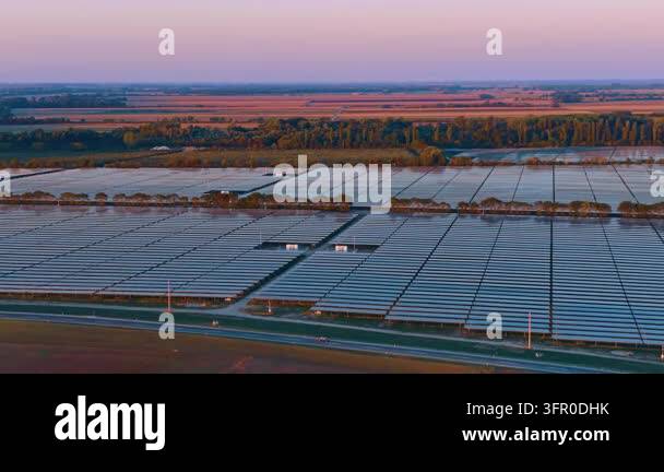 Photovoltaic farm, aerial view across panel rows at dusk. A road ...