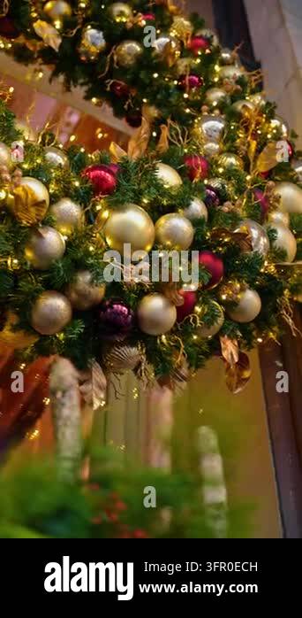 Christmas baubles and metallic leaves decorate a green garland. Small ...