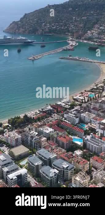 Aerial view of a curved beach, harbor breakwaters, cruise ship, and ...