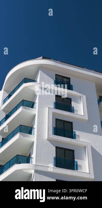 Upward view of a contemporary white residential building with curved ...