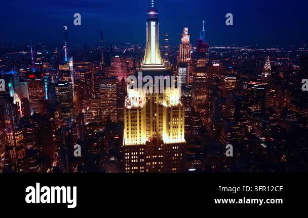 Illuminated Empire State Building spire over Manhattan at night. White ...