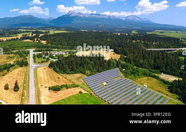 Solar panel rows beneath a mountain range and forest. Reflective ...