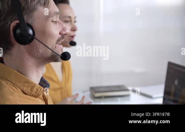 Focused male call center operator in yellow casual shirt is assisting ...