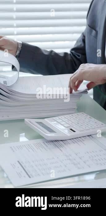 Business person working on financial paperwork, reviewing stacked ...