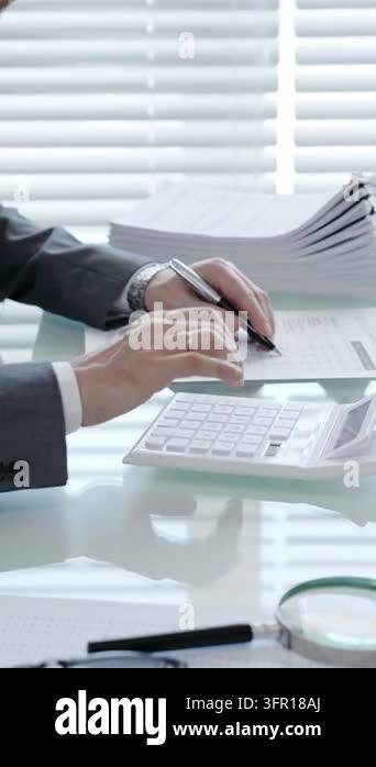 Business person hands operating a calculator and holding a pen, working ...