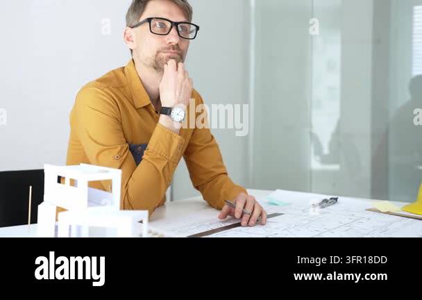Professional man in glasses and a mustard shirt sitting at a desk ...