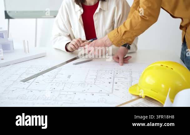 Architects and engineers analyze detailed building plans, using compass ...