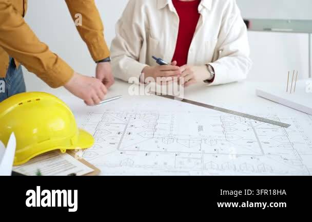 Architects and engineers analyze detailed building plans, using compass ...