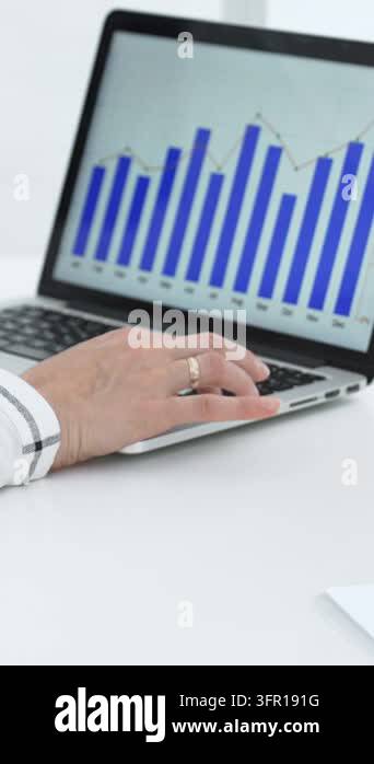 Business hands on a laptop keyboard with a bar graph and line chart on ...