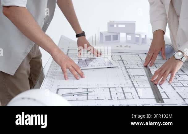 Architects hands reviewing blueprint plans on a table, collaborating on ...