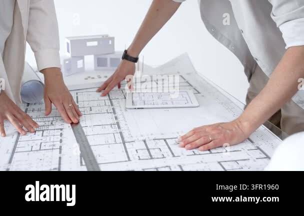 Architects hands reviewing blueprint plans on a table, collaborating on ...