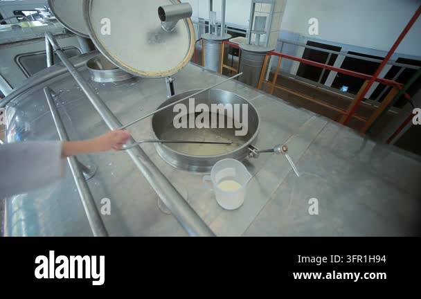Dairy factory worker stirring milk large steel vat mixing paddle. Food ...