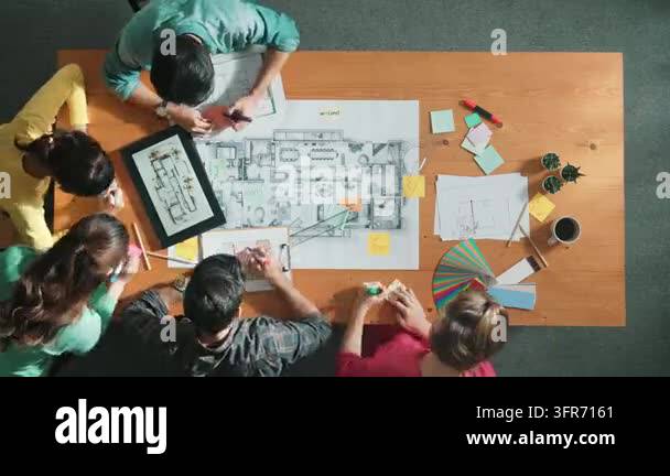 Top down aerial view of smart engineer looking at blueprint at meeting ...