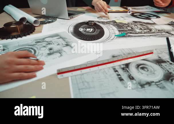 A team of engineers collaborates on technical drawings and diagrams of ...