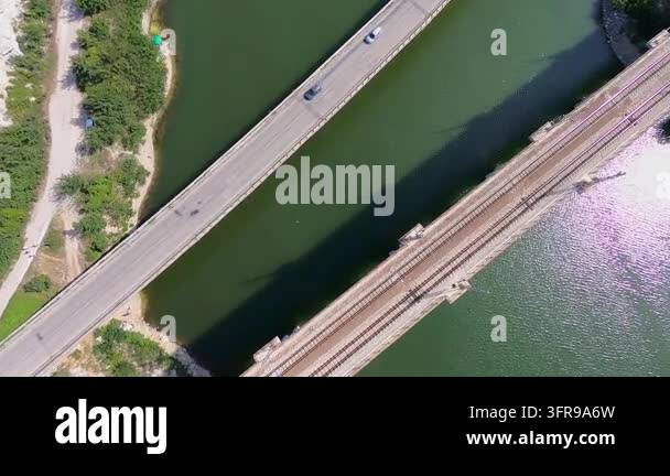 Parallel Shadows Zenital aerial shot of cars driving over a concrete bridge crossing a ...