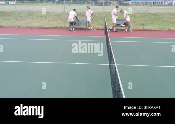 Overlay Html Over Video Four tennis players ending session, collecting gear at baseline while ...