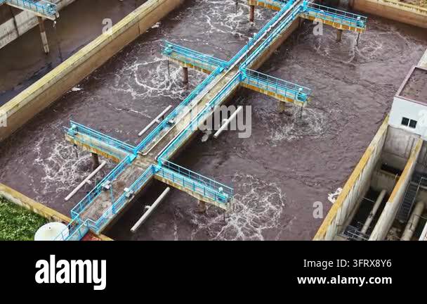 Several workers operate equipment at a wastewater treatment facility ...