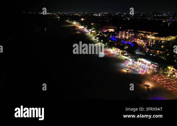 Aerial view of a beach at night with lights from nearby buildings and ...