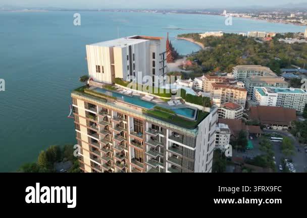 Modern high-rise building with a rooftop pool overlooking the ocean and ...