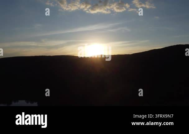 Sun setting behind rolling hills under a clear sky Stock Video Footage ...