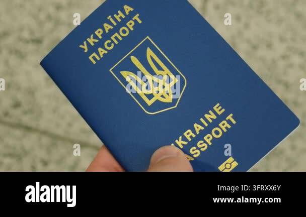 Ukrainian biometric passport in male hand near transport terminal floor ...