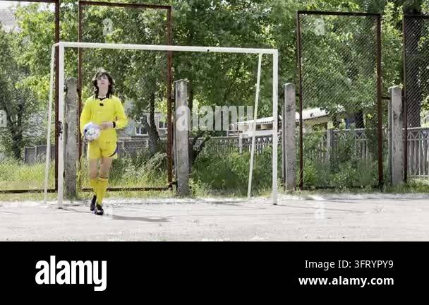 Teen boy training football skills and coordination on outdoor court ...