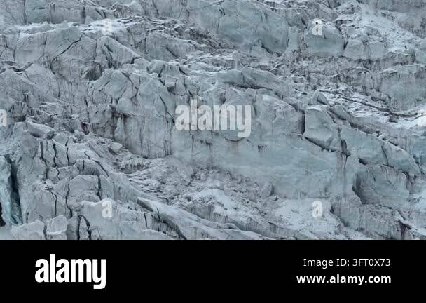 Aerial drone footage slowly tracking over a vast, textured glacier with ...