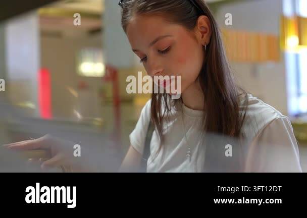 Focused young woman using a digital touch screen at a self service ...