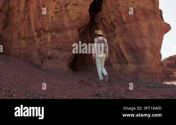 A woman with a backpack enters the cave. beautiful cliffs and landscape ...