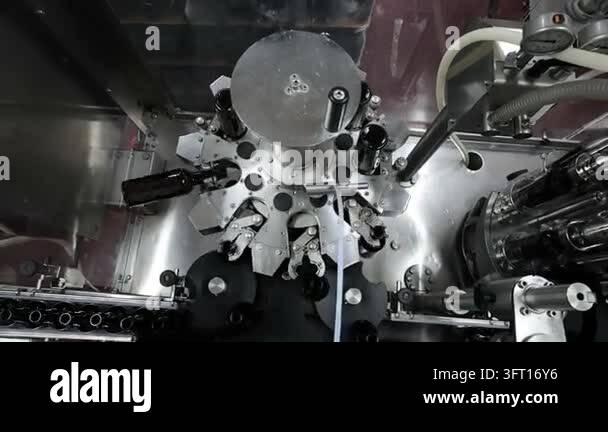 Overhead view of an automated wine bottling machine processing dark ...