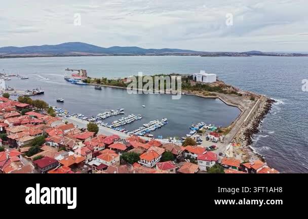 The scene shows a coastal area with a marina filled with boats. Red ...
