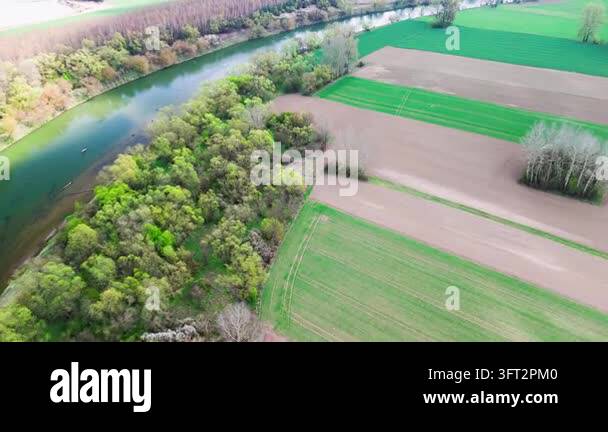 Aerial Spring Aerial view of a curving river framed by fresh green trees beside ...