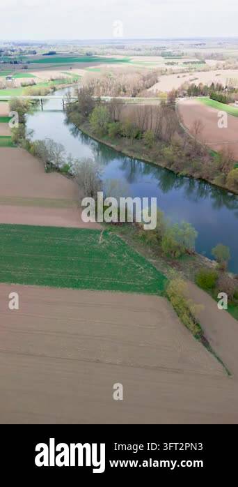 Aerial Spring Under hazy spring sky, a calm river runs toward a distant road bridge ...