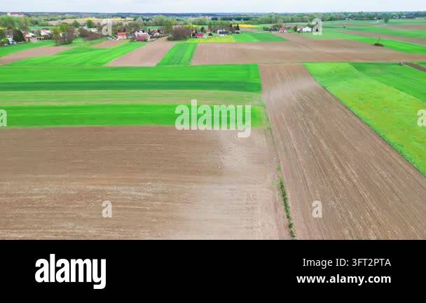 Aerial Spring Under a bright spring sky, patchwork green and brown farm fields spread ...