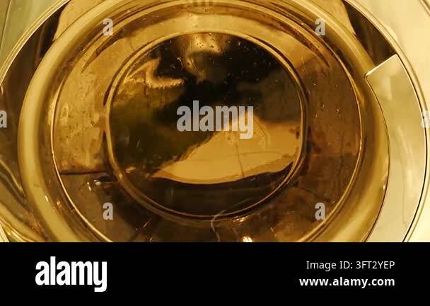 Spinning washing machine drum glowing in warm amber light, swirling ...