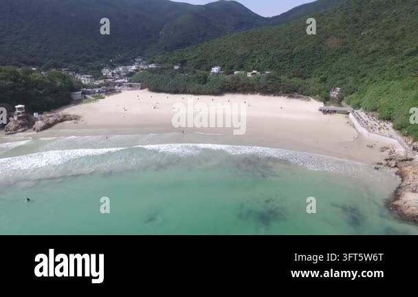 Aerial drone footage captures a serene beach with gentle waves and lush ...