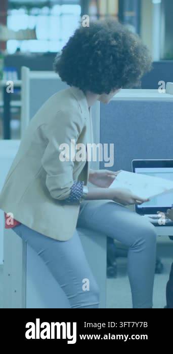 Vertical video: Woman opening doc at desk, tapping laptop, causing ...