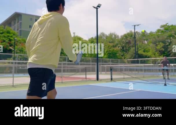 Back Outside Four people playing pickleball on an outdoor court, hitting the ball ...