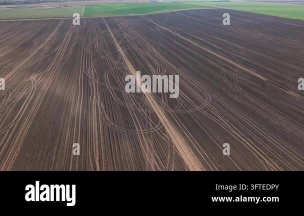 Aerial drone view reveals tractor tire tracks crossing freshly plowed ...