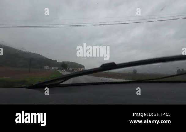 Car driving on a wet rural road in Vall d'en Bas on a rainy and cloudy ...