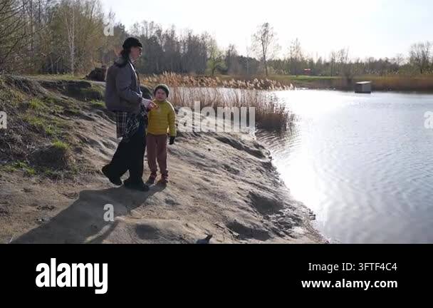 Fish Audio Parent and children spend time by the lake, throwing stones and looking ...