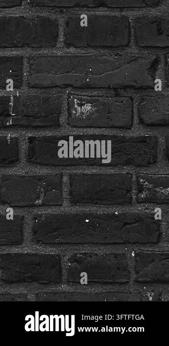 A weathered dark grey brick wall texture with visible mortar lines ...