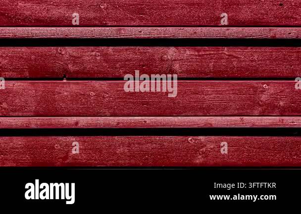 A close-up view of horizontally aligned weathered red wooden planks ...
