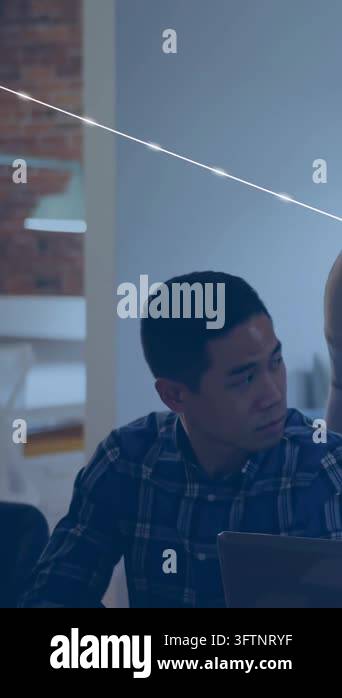 Vertical video: Seated man typing, peer leaning, blue icons layering ...