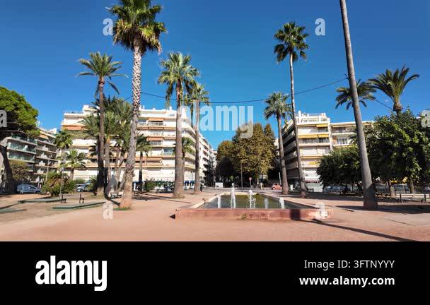 Tsll Tree Antibes, France - September 15, 2026 - Sunny urban park with a water ...