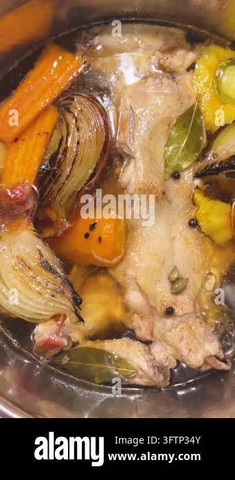 A chef prepares a traditional hot soup base, cooking chicken stock in a ...