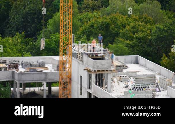 Tsll Tree Construction workers build a modern concrete building against green ...