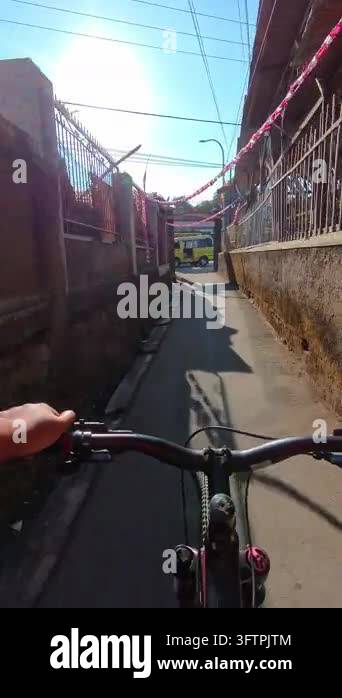 First-person Video of Bicyclist rides down narrow, sunlit alleyway ...
