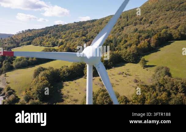 Tsll Tree A wind turbine stands tall in a green field surrounded by hills and ...