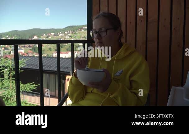 woman wearing yellow hoodie glasses having breakfast terrace country ...